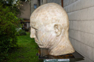 Monumentale Skulptur eines Kopfes von Virgilius Moldovan im Garten bei der Ausstellung "Brennende Wälder und die Schönheit der Natur" bei Eva Jansenberger (Kuratorin, Kunst- und Philosophieverein Triebenstein), Trieben, August 2024, (c) Tom Monochrom