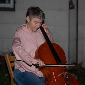 Die Cellistin Andrea Grasmugg von der Band Rolandrea im Garten von Eva Jansenberger bei der Vernissage zur Ausstellung Möbiusflächen in Trieben 2023, (c) Tom Monochrom